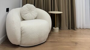 A modern living room with a white, textured sofa, a round floor lamp, and a small side table.