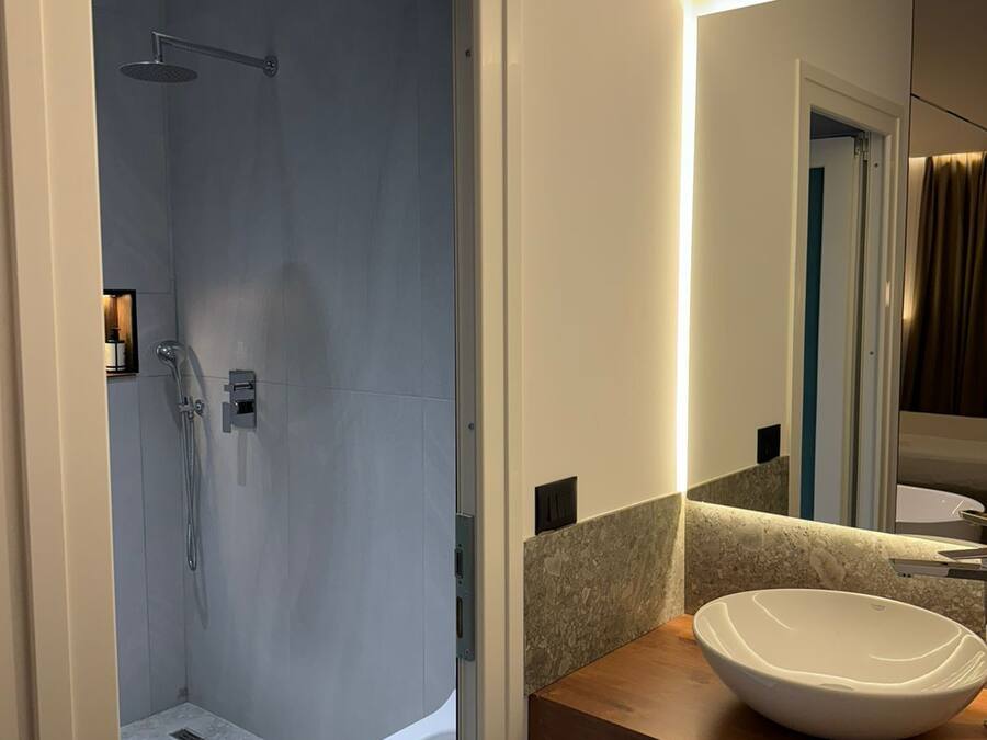 Un baño moderno con cabina de ducha, inodoro y tocador con lavamanos grande.