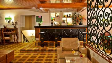 A bar area with stools, a bar counter, and a variety of bottles.