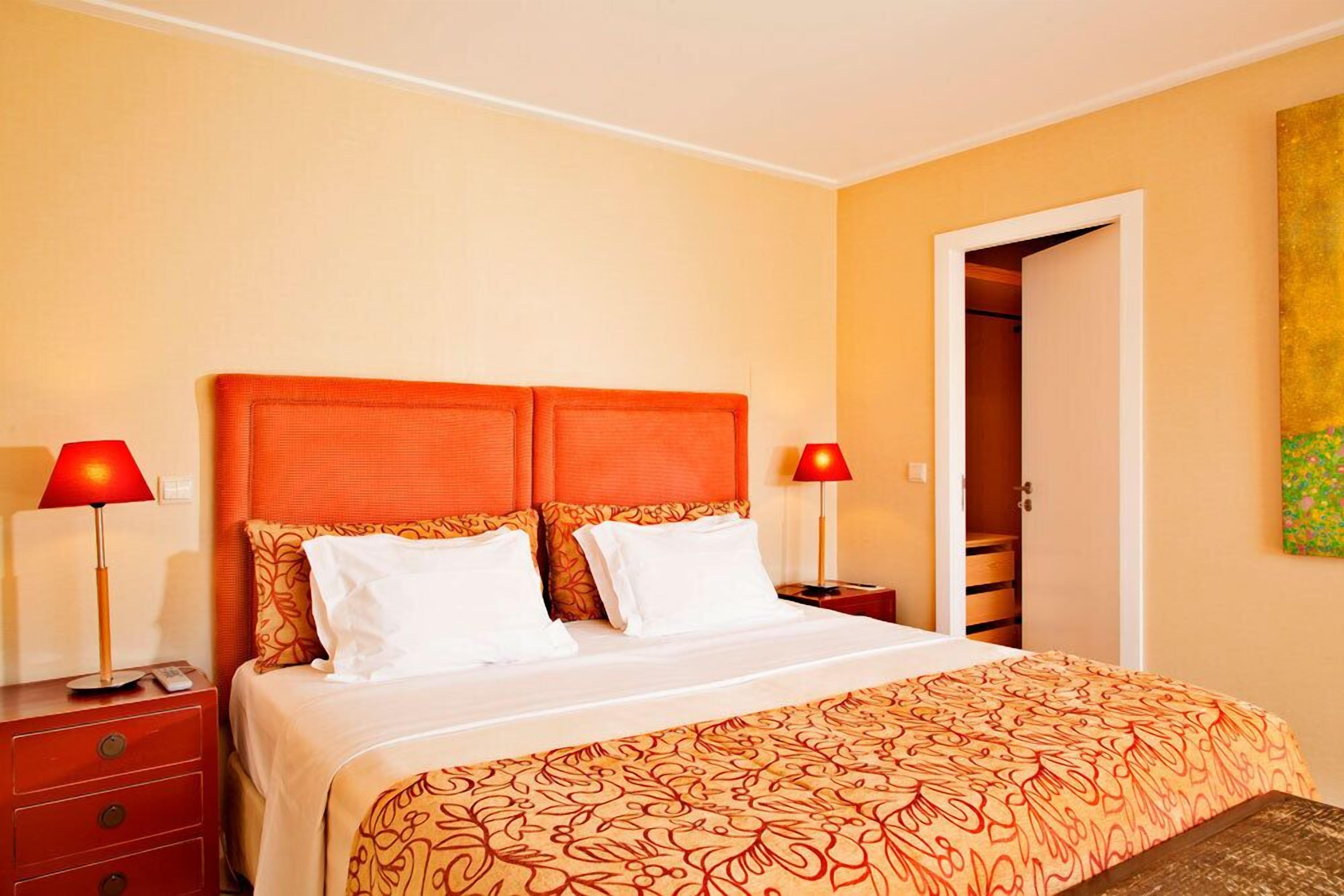 Una camera d'albergo con un letto grande, due comodini e una porta che dà accesso a un armadio.