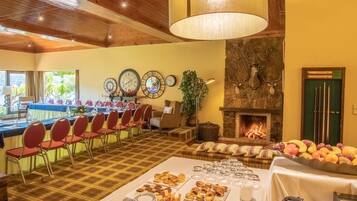 Un comedor con una larga mesa dispuesta para una comida, una chimenea y varios relojes en la pared.