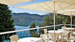 Una terraza con mobiliario exterior, vistas a un lago y abundante vegetación.