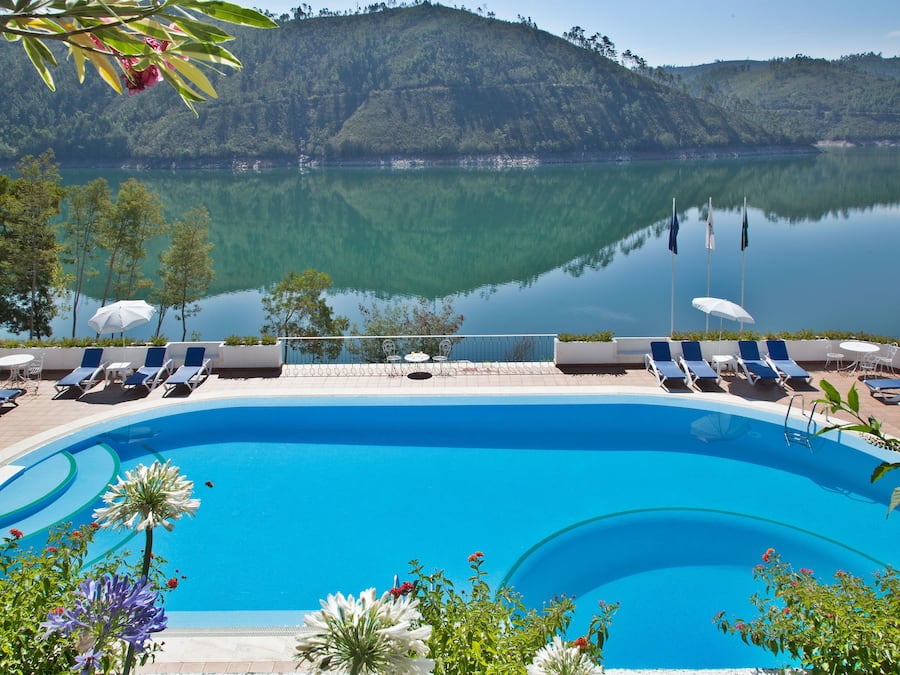 Een buitenzwembad, parasols bij het zwembad en ligstoelen