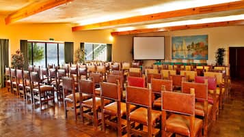 A conference room with rows of wooden chairs and a projector screen.