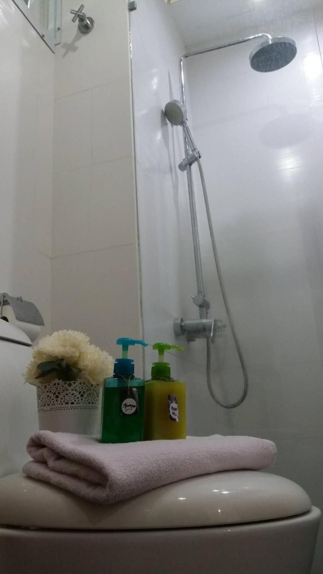 A bathroom with a shower, a toilet, and toiletries on the sink.