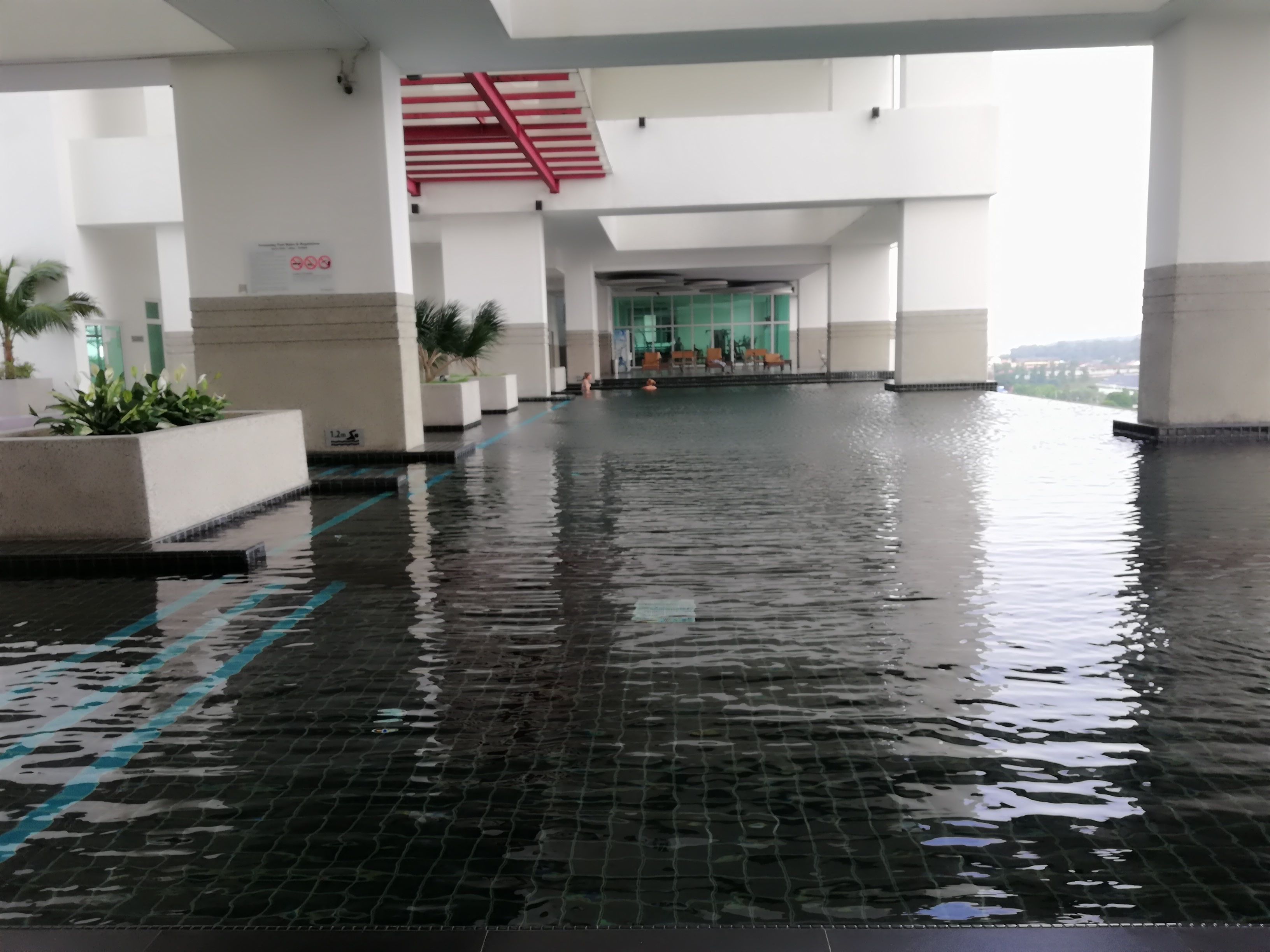An indoor swimming pool with tiled flooring and a red staircase.