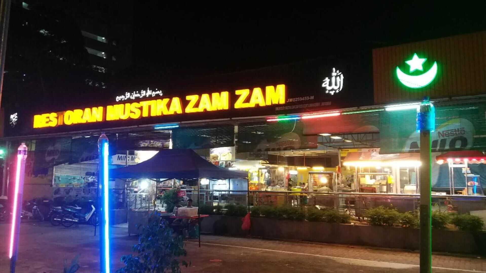 Un restaurante llamado "Mustika Zam" con terraza y un letrero de neón.