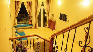 A staircase with ornate black railings leading to a room with a sofa, a guitar, and a television.