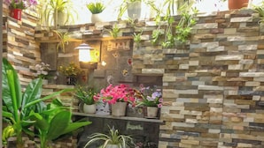 A garden area with a stone wall, potted plants, a white picket fence, and decorative chickens and eggs. - Jolie House (Lam Vien - Da Lat)