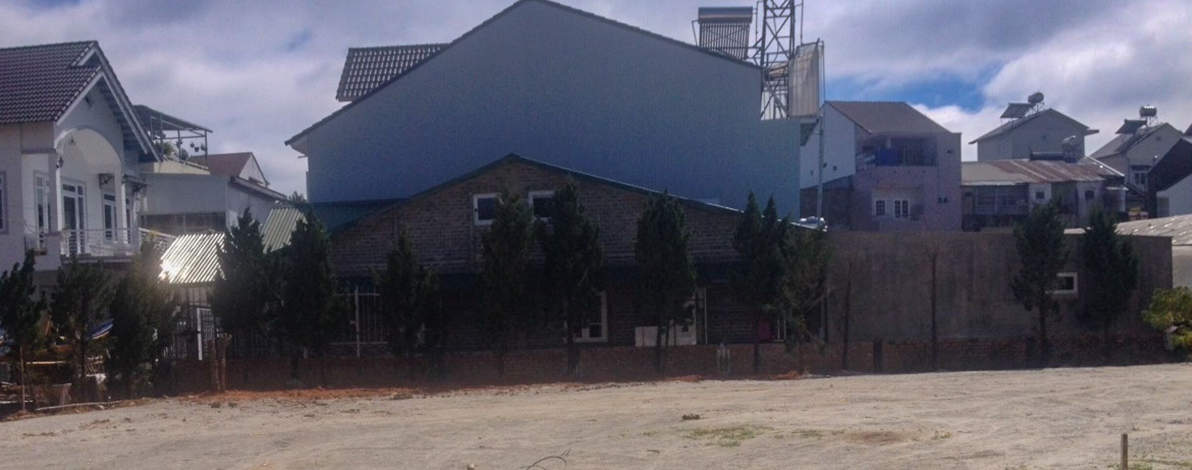 A large industrial building with a flat roof and a tall chimney, surrounded by residential houses with pitched roofs.