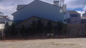 A large industrial building with a flat roof and a tall chimney, surrounded by residential houses with pitched roofs.
