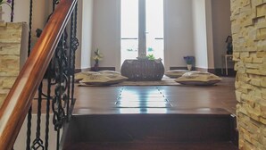 A staircase with a wooden handrail leading to a landing with a large window. - Jolie House (Lam Vien - Da Lat)