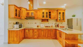 A kitchen with wooden cabinets, a microwave, a toaster, and a refrigerator.