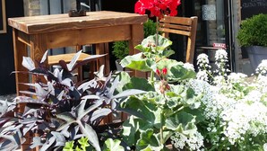 A restaurant named ARHIV with a wooden sign, outdoor seating, and potted plants. - Hotel Arhiv (Novi Sad)