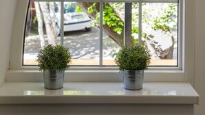 A window with a view of greenery and a parked car outside. - Hotel Arhiv (Novi Sad)