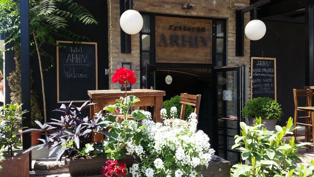 A restaurant named ARHIV with a wooden signboard, a blackboard menu, and a welcoming sign. - Hotel Arhiv (Novi Sad)