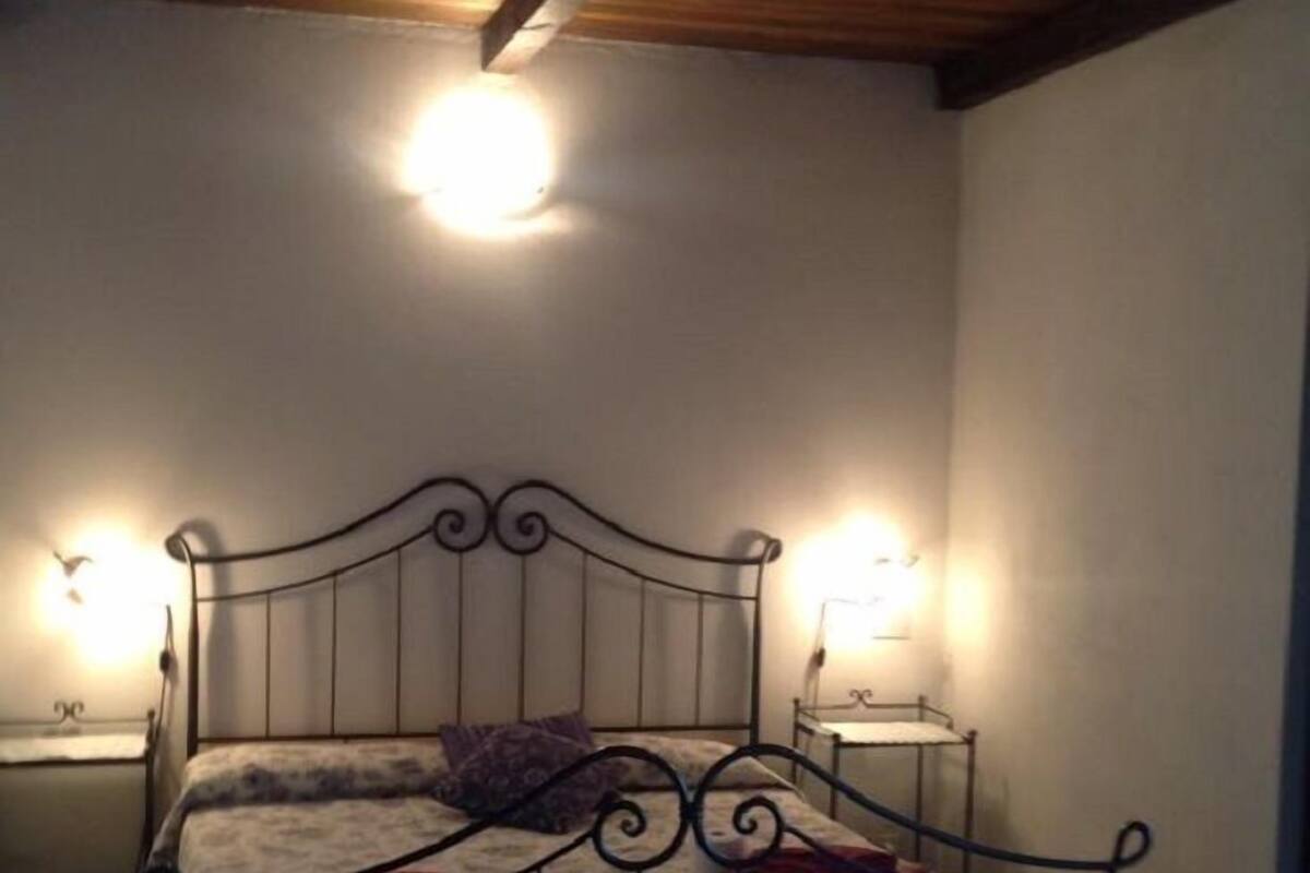 A bedroom with a metal bed frame, two bedside tables with lamps, and a wooden ceiling.