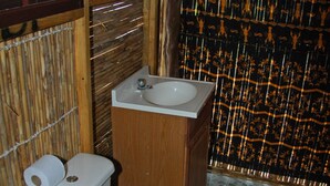 A bathroom with a toilet, sink, and bamboo wall.