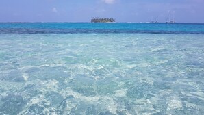 A clear view of turquoise ocean water with a small island in the distance.