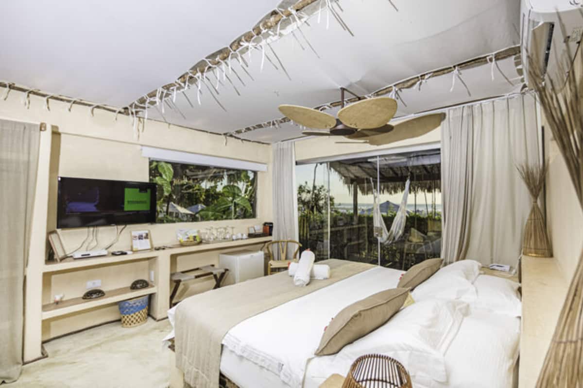 A bedroom with a bed, a desk, a television, and a window with a view.
