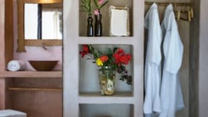 A bathroom with a mirror, a sink, a shelf with a vase of flowers, and a towel rack. - Casa de Areia (Jijoca de Jericoacoara)