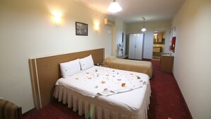 A hotel room with a large bed, a smaller bed, a desk, and a wardrobe. - Aykut Palace Otel (Iskenderun)