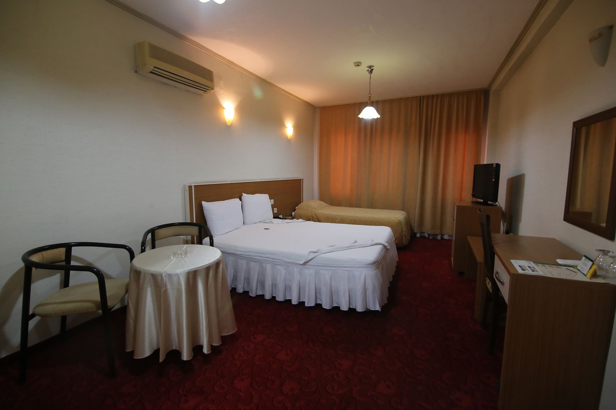 Una habitación de hotel con cama, escritorio, silla, mesita y televisor.