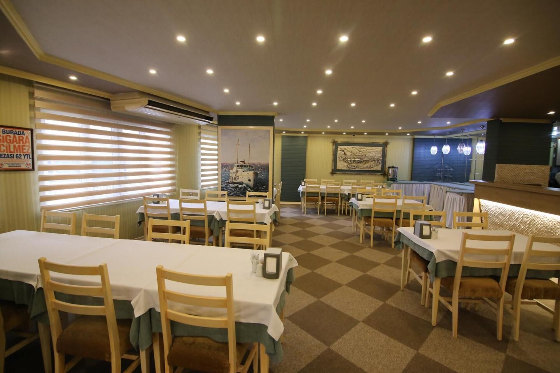 A restaurant with multiple tables and chairs, a checkered floor, and a painting on the wall.