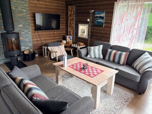 A cozy living room with a fireplace, a sofa, a coffee table, and a television. - Heinåli Hytta (Rauma)