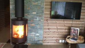 Un foc de llenya encès, un rellotge i una televisió penjada a una paret de fusta.