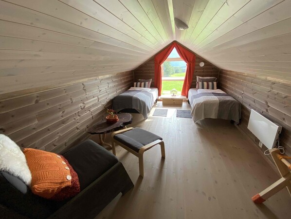 A cozy attic bedroom with two beds, a small table, and a bench. - Heinåli Hytta (Rauma)