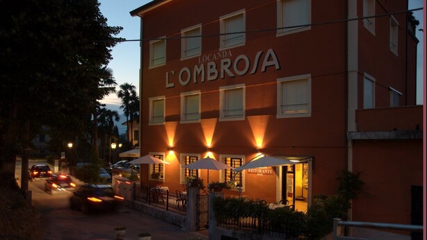 A building with the sign 'LOMBROSA' and 'RISTORANTE BAR' indicating a restaurant bar. There are outdoor seating areas with umbrellas and potted plants. - Hotel Locanda l'Ombrosa (Vezzano Ligure)