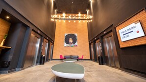 A modern lobby with a central seating area, a large mural on the back wall, and a sign indicating the conference rooms. - ONOMO Hotel Casablanca City Center (Casablanca)