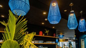 A bar area with blue hanging lights, a counter, and shelves with glasses and bottles. - ONOMO Hotel Casablanca City Center (Casablanca)