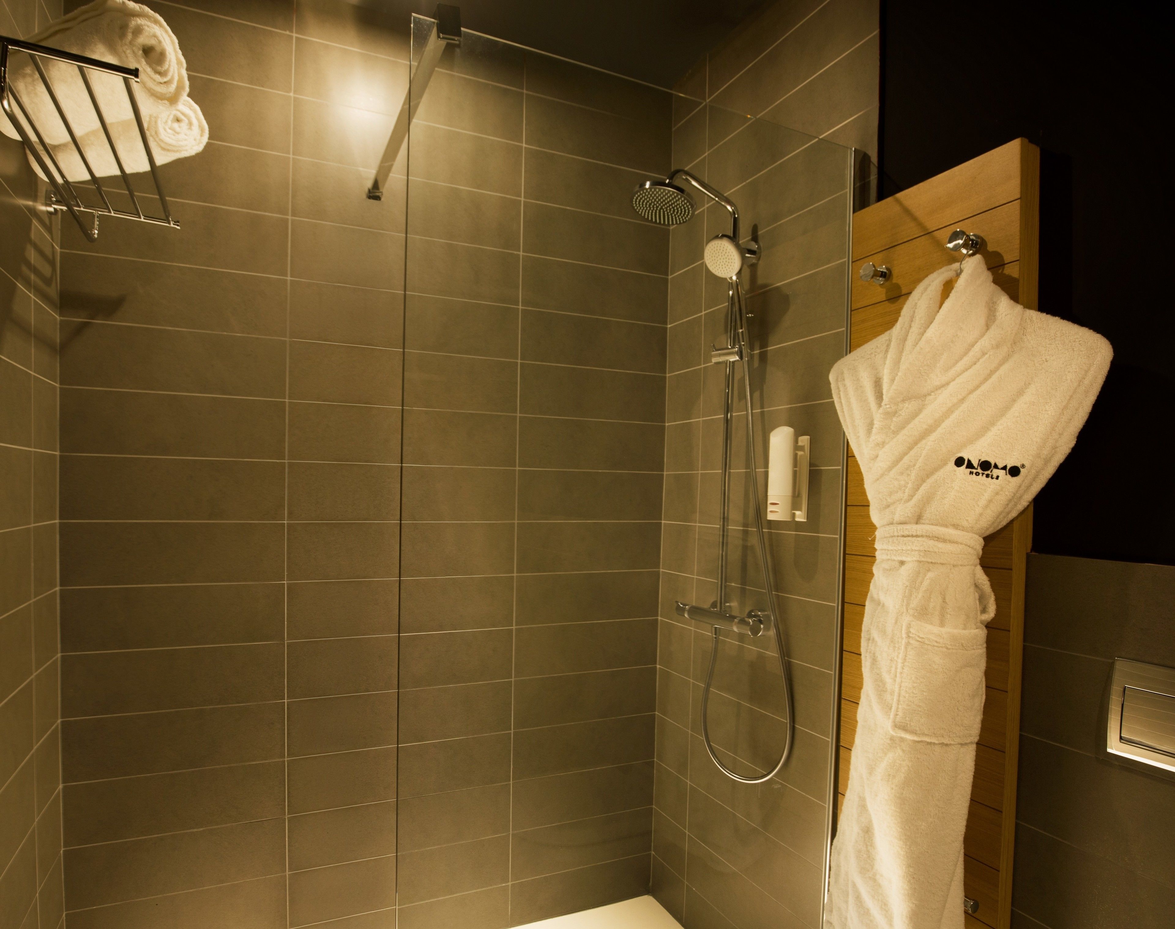 A modern bathroom with a glass-enclosed shower, a wooden door, and a towel rack with a folded towel.