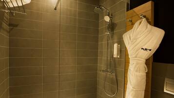 A modern bathroom with a glass-enclosed shower, a wooden door, and a towel rack with a folded towel.