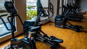 A gym with multiple treadmills lined up along a wall with large windows.