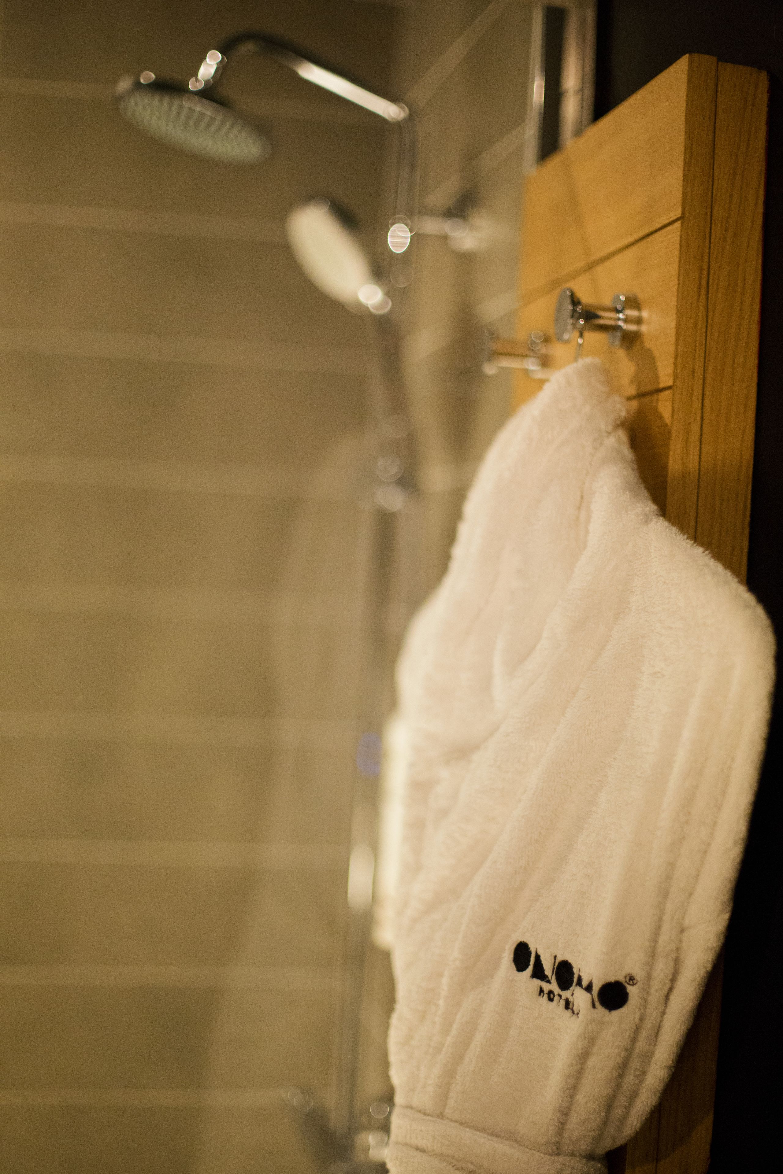 A white towel hanging on a wooden door in a bathroom with a shower head above it.