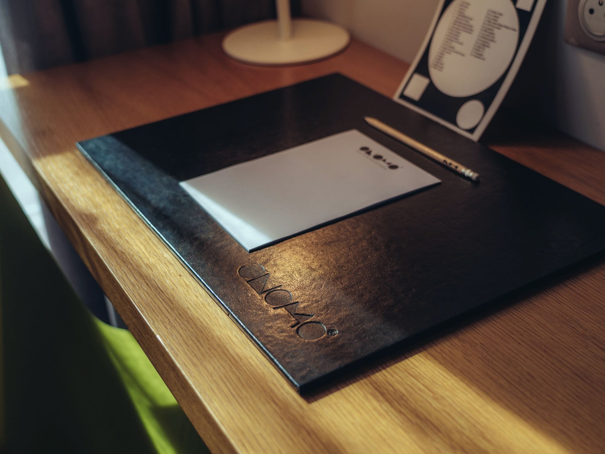 Una mesa de madera con una carpeta negra y una hoja de papel blanca encima.