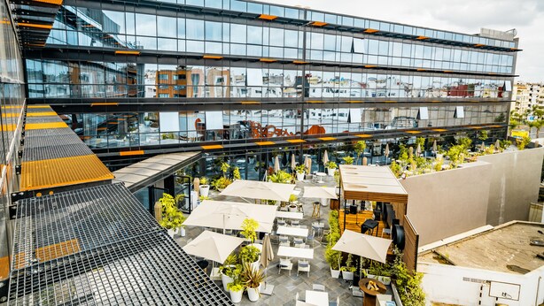 A modern building with multiple floors, outdoor seating areas with umbrellas, and potted plants. - ONOMO Hotel Casablanca City Center (Casablanca)