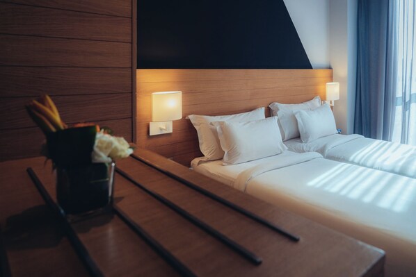 A hotel room with a wooden headboard, two bedside tables, a bed with white bedding, and a vase with flowers on the left side.