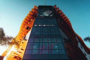 A hotel with a modern glass facade and a distinctive orange and red architectural design.