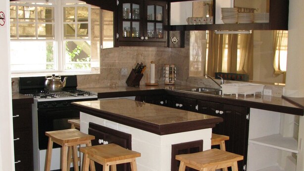 Una cocina moderna con una isla central, taburetes de bar y un ventanal que proporciona luz natural.