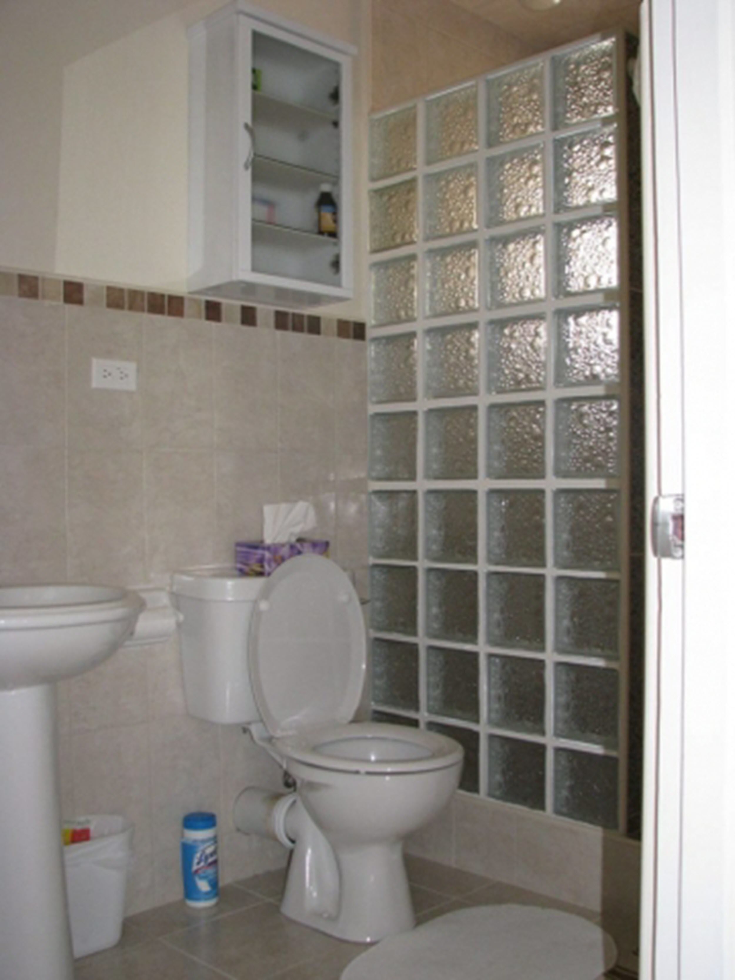 A bathroom with a toilet, sink, and cabinet.