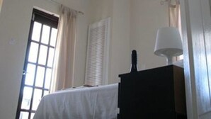 Una habitación con techo inclinado, cama, cómoda y ventana con cortinas.