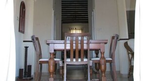 Un comedor con una mesa, sillas, una araña y un ventanal con persianas.