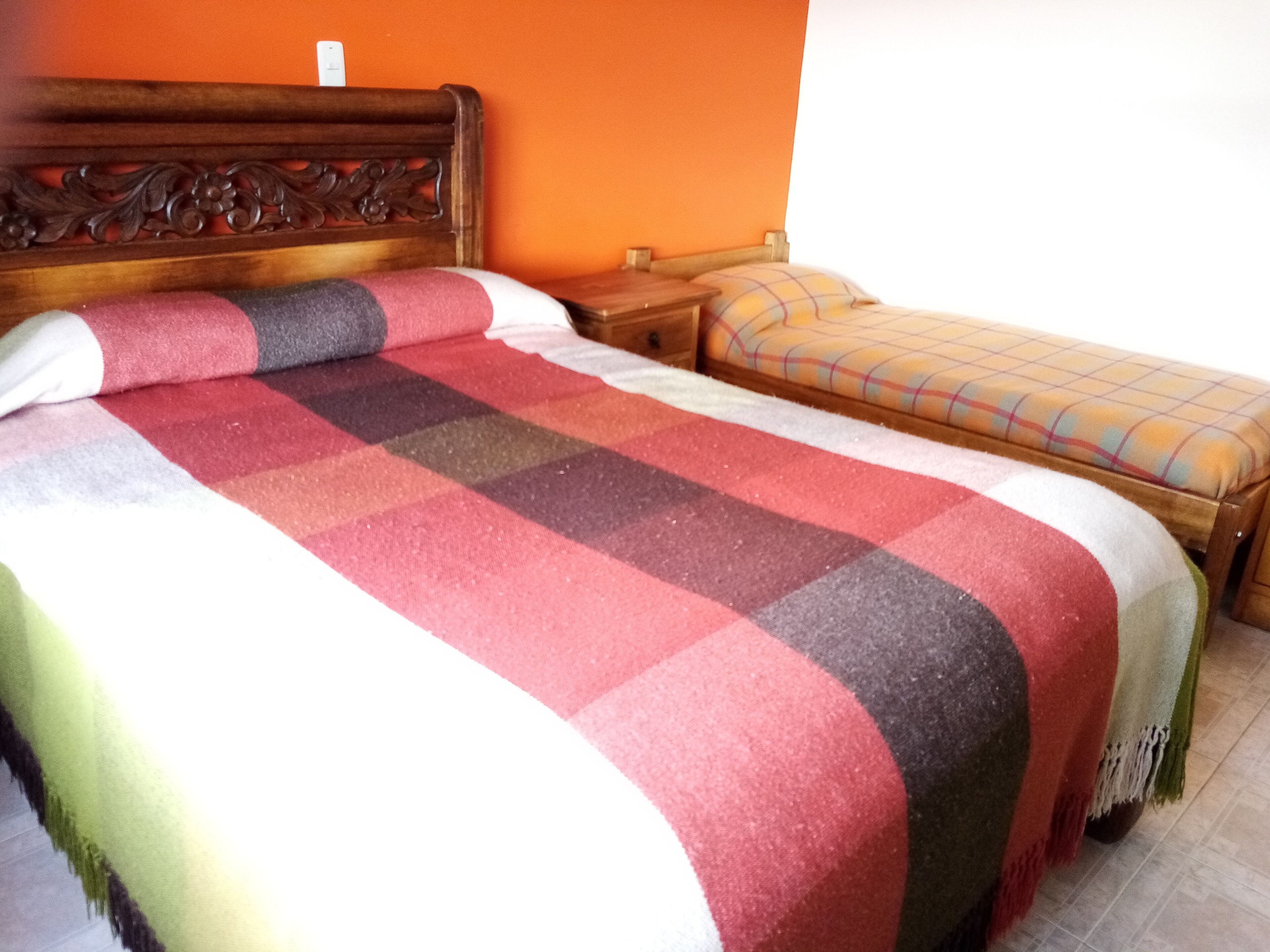 Una cama doble con un edredón colorido y un cabecero de madera.