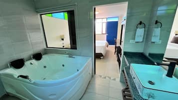 Un baño moderno con una bañera independiente grande, un lavamanos con cerramiento de vidrio y un espejo sobre el lavamanos.