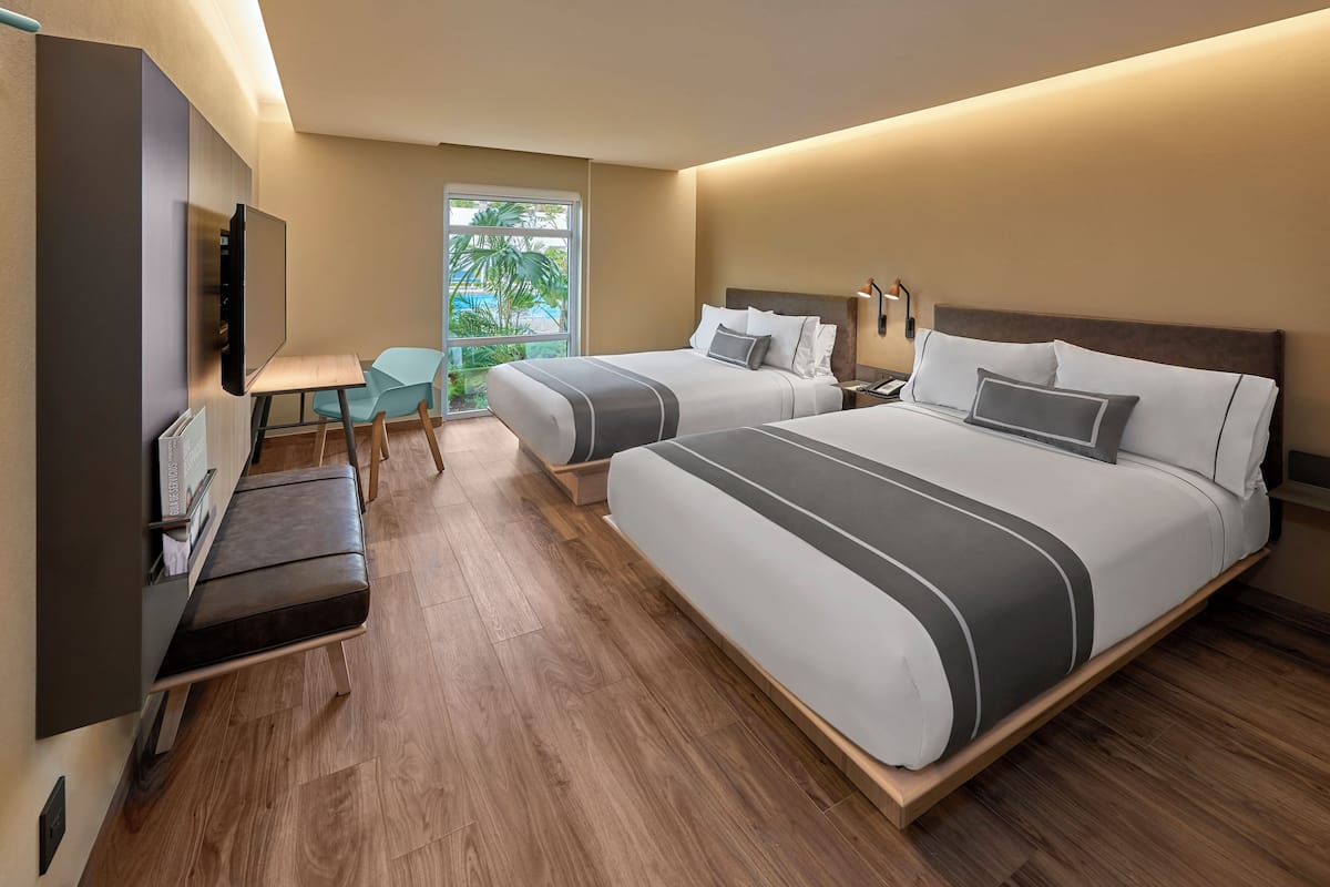Ein Hotelzimmer mit zwei Betten, einem Fernseher, einem Schreibtisch und Blick ins Freie.