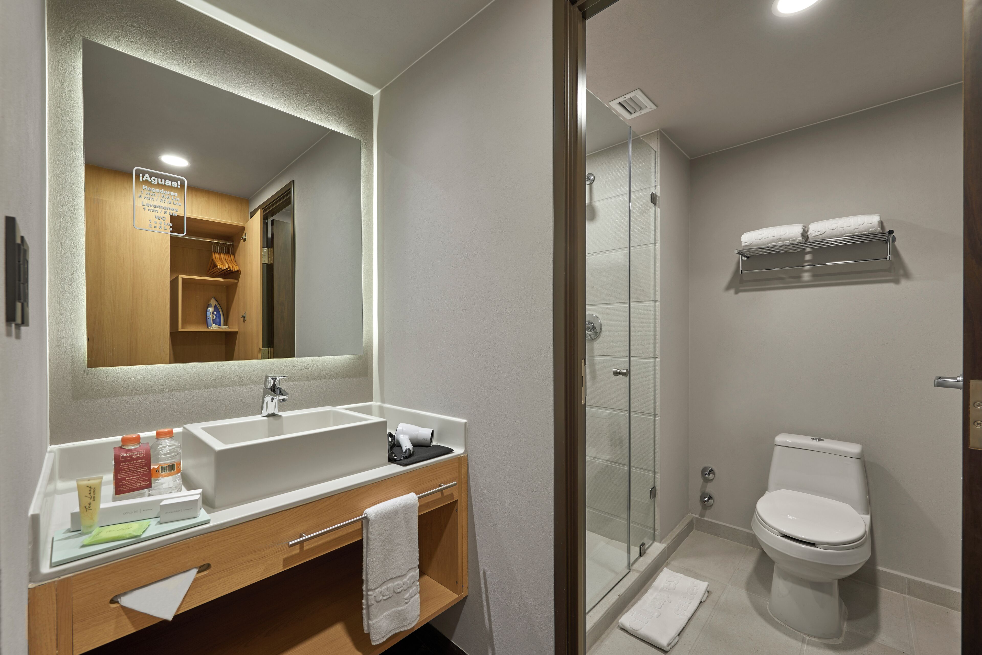 Une salle de bain moderne avec un grand miroir, un lavabo, des toilettes et une douche.